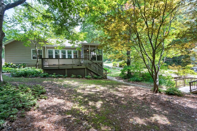 rear view of house featuring a sunroom and a wooden deck