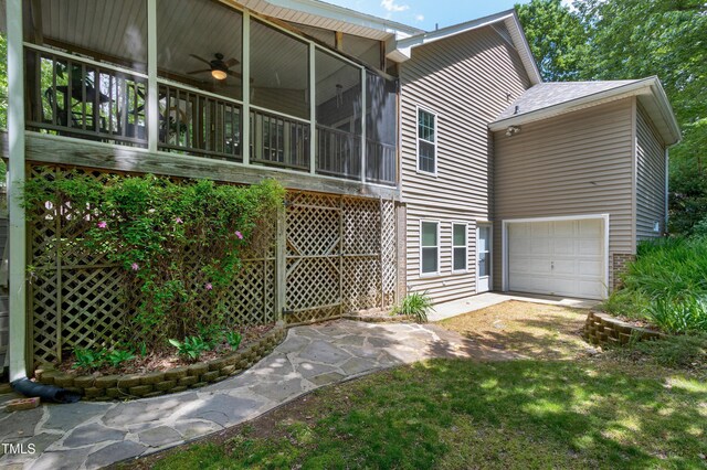back of property with a sunroom, ceiling fan, driveway, and an attached garage