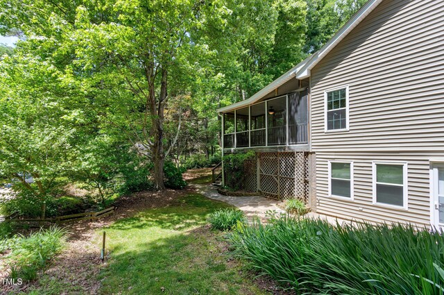 view of grassy yard with a sunroom
