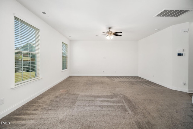 carpeted spare room featuring a ceiling fan and baseboards