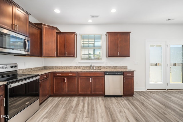 kitchen with appliances with stainless steel finishes, light wood-style floors, a sink, light stone counters, and recessed lighting