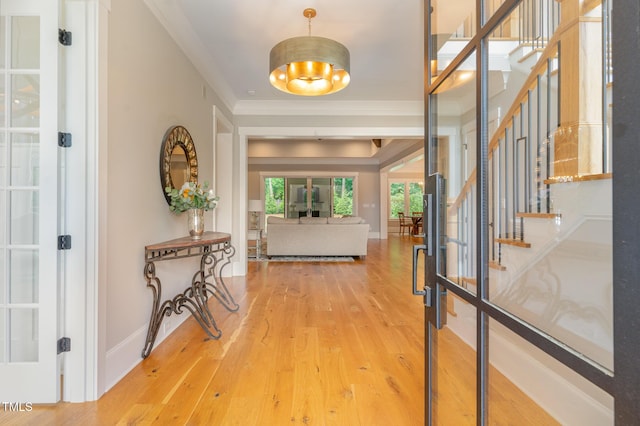 foyer with stairs, wood finished floors, baseboards, and crown molding