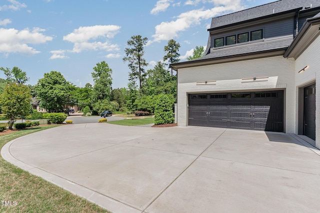 view of property exterior with brick siding, a garage, and concrete driveway