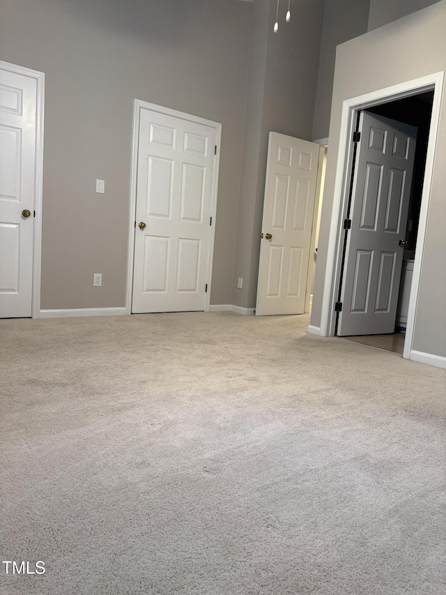 unfurnished bedroom featuring carpet flooring, baseboards, and a high ceiling