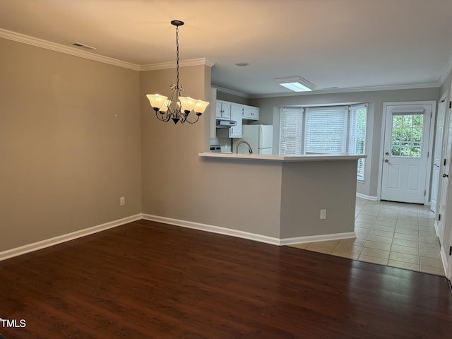 spare room featuring ornamental molding, light wood-type flooring, a chandelier, baseboards, and a sink