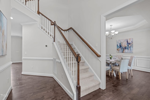 stairs featuring ornamental molding, wood finished floors, and a chandelier