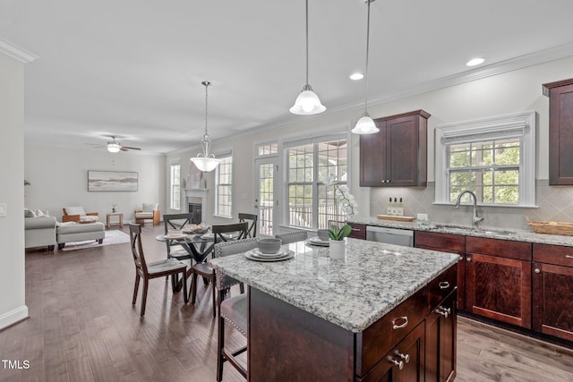 kitchen with a sink, stainless steel dishwasher, ornamental molding, plenty of natural light, and open floor plan