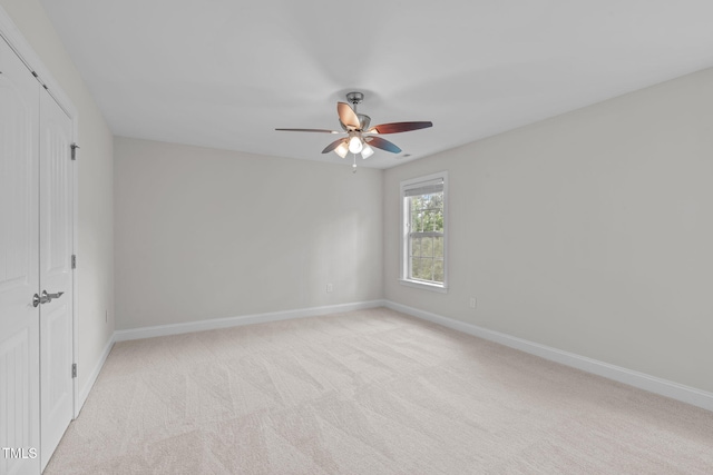unfurnished bedroom with baseboards, light colored carpet, a ceiling fan, and a closet