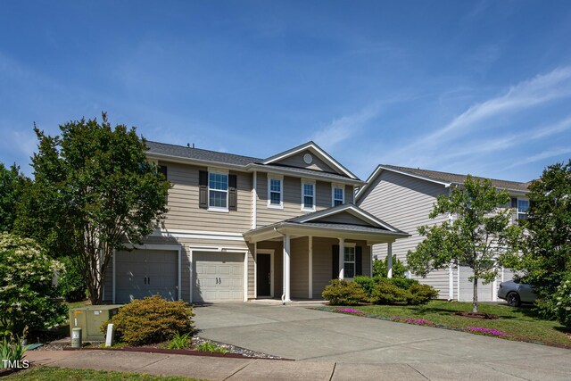 multi unit property featuring a garage, concrete driveway, and covered porch