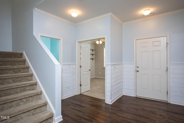 entrance foyer with dark wood-type flooring, ornamental molding, stairs, and a wainscoted wall