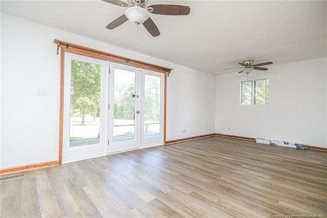 spare room featuring a ceiling fan, light wood finished floors, baseboards, and baseboard heating