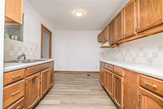 kitchen with a sink, brown cabinetry, and backsplash