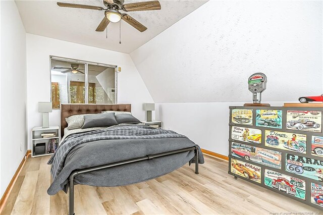 bedroom featuring wood finished floors, vaulted ceiling, baseboards, and ceiling fan