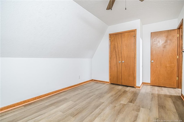 additional living space with light wood finished floors, baseboards, a textured ceiling, ceiling fan, and lofted ceiling