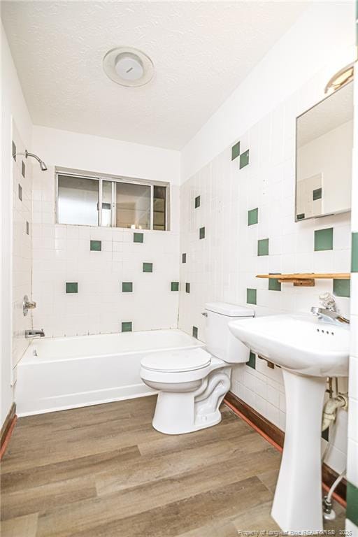 full bath featuring tile walls, toilet, wood finished floors, bathtub / shower combination, and backsplash