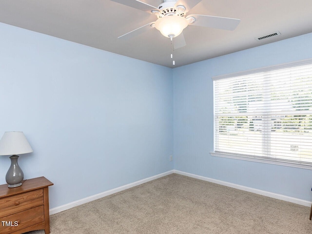 carpeted spare room with baseboards and a ceiling fan