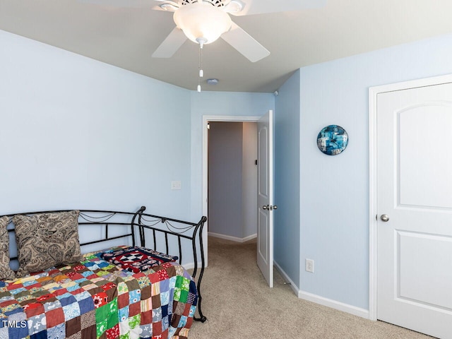 bedroom featuring light colored carpet, baseboards, and a ceiling fan