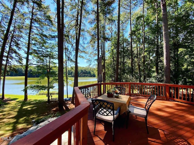 deck with a water view, outdoor dining area, a yard, and view of scattered trees