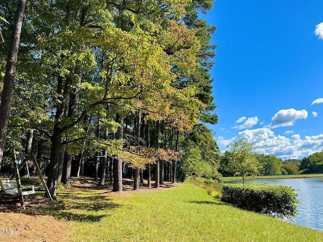 view of property's community featuring a water view, a view of trees, and a lawn