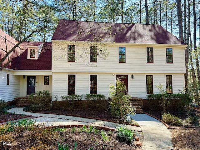 colonial inspired home featuring roof with shingles