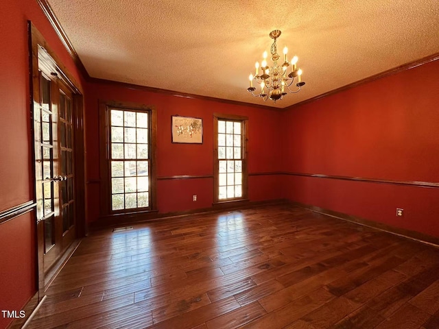 empty room featuring a textured ceiling, a chandelier, crown molding, and hardwood / wood-style floors