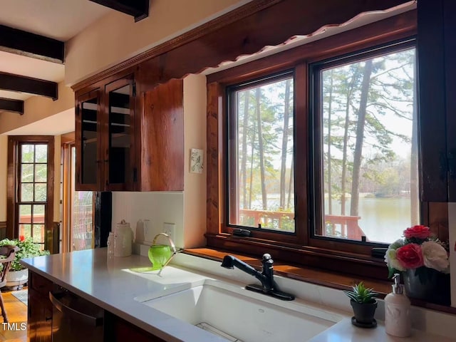 kitchen view of a sink, light countertops, and glass insert cabinets