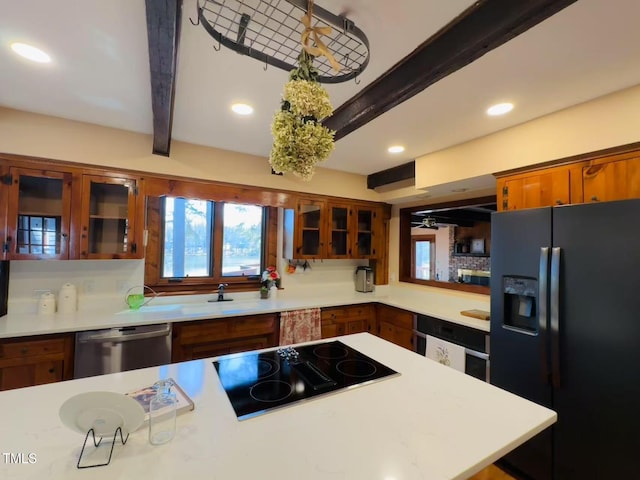 kitchen featuring black appliances, beamed ceiling, brown cabinets, light countertops, and glass insert cabinets