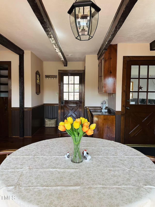 dining room featuring beam ceiling, wainscoting, and wood finished floors