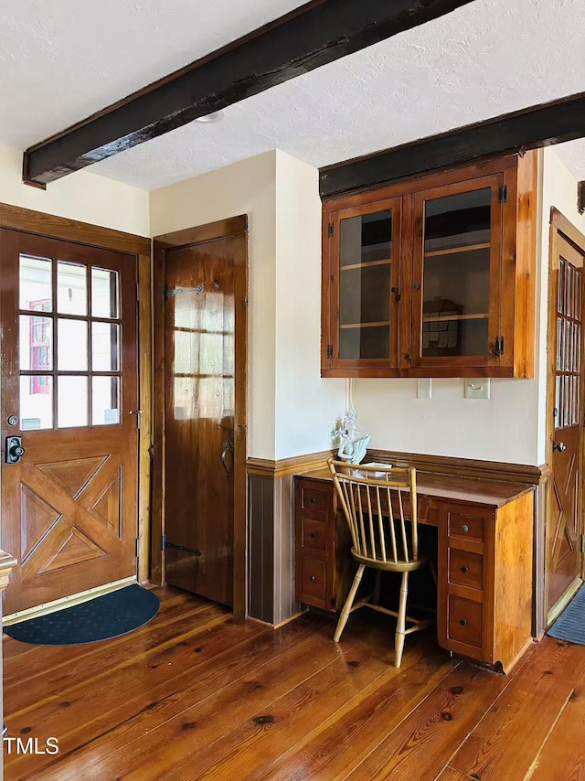 entryway with beamed ceiling, dark wood-style flooring, and wainscoting