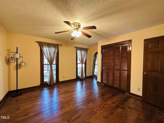 unfurnished bedroom with wood finished floors, a textured ceiling, a closet, baseboards, and ceiling fan