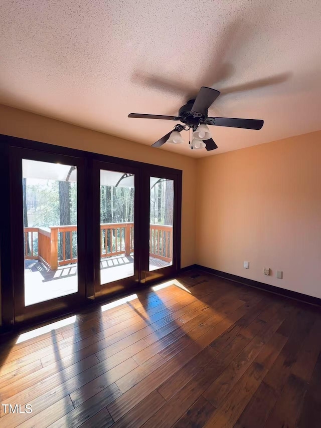 spare room featuring a textured ceiling, a ceiling fan, wood-type flooring, and baseboards