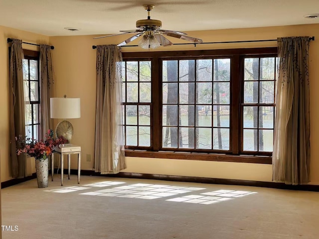 carpeted empty room featuring a ceiling fan and baseboards