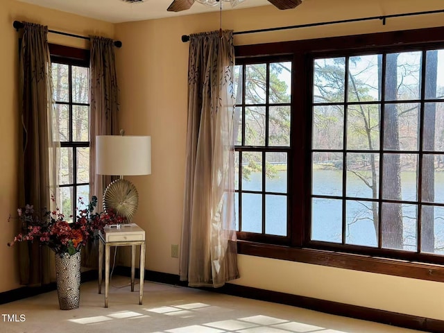 entryway with a water view, a ceiling fan, and baseboards