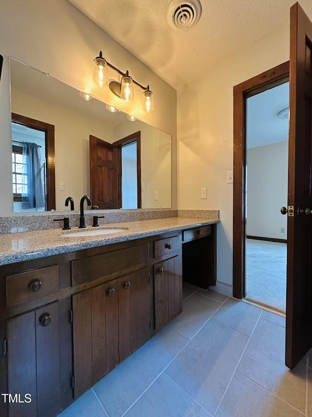 bathroom with tile patterned flooring, a textured ceiling, and vanity