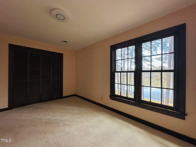 unfurnished bedroom with multiple windows, light colored carpet, and baseboards