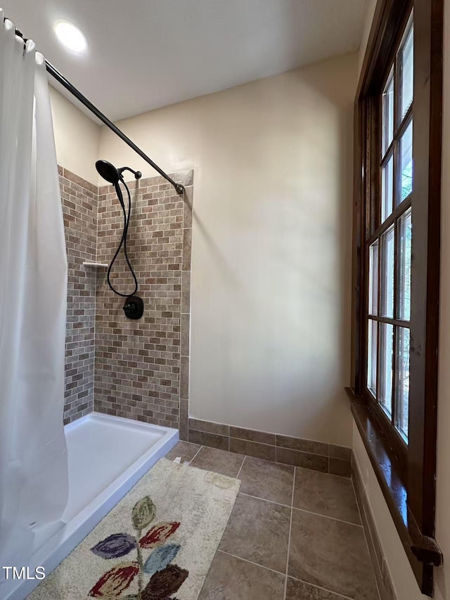 full bath featuring a shower stall, plenty of natural light, baseboards, and tile patterned floors