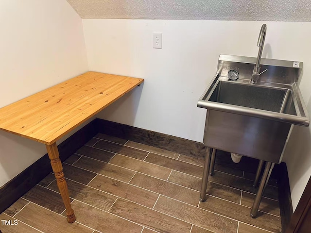 kitchen featuring wood tiled floors, a textured ceiling, and a sink