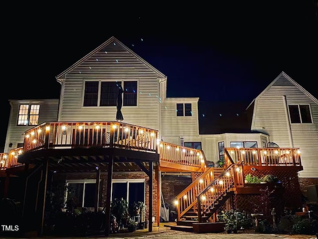 back of house at twilight featuring a wooden deck and stairs