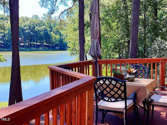 deck with a water view and outdoor dining space