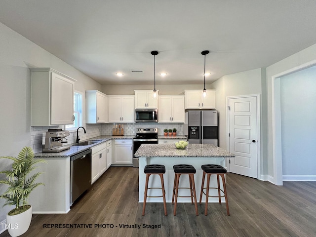 93 Butterbean Ct, Zebulon, NC 27597 - kitchen featuring appliances with stainless steel finishes, a sink, dark wood-style flooring, a kitchen island, and light stone countertops