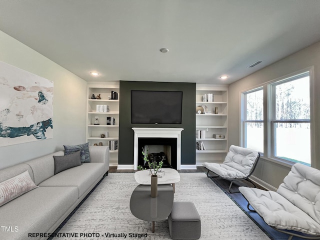 93 Butterbean Ct, Zebulon, NC 27597 - living area featuring healthy amount of natural light, built in shelves, wood finished floors, a fireplace, and recessed lighting