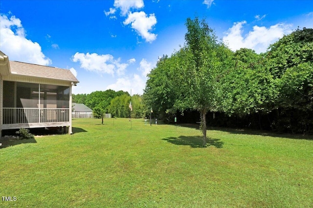 view of green lawn with a sunroom