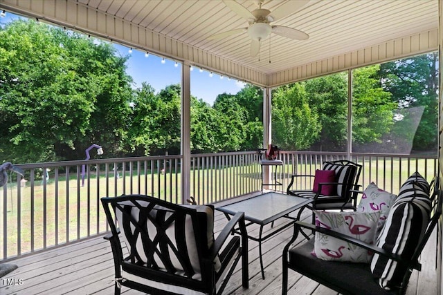 wooden deck featuring a ceiling fan, a yard, and view of wooded area