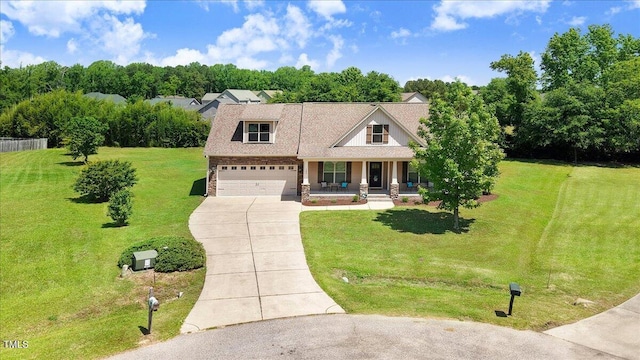 view of front of home with covered porch, concrete driveway, a front lawn, stone siding, and view of scattered trees