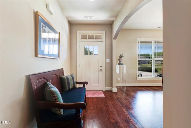 foyer entrance featuring arched walkways, wood finished floors, and baseboards