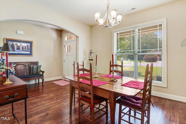 dining area with arched walkways, a chandelier, wood finished floors, and baseboards
