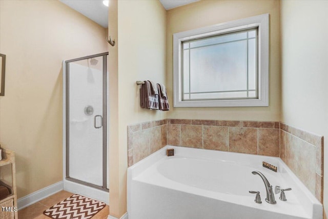 full bath with a stall shower, a bath, baseboards, and tile patterned flooring