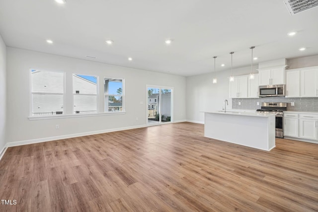 kitchen featuring appliances with stainless steel finishes, light wood finished floors, recessed lighting, tasteful backsplash, and light countertops