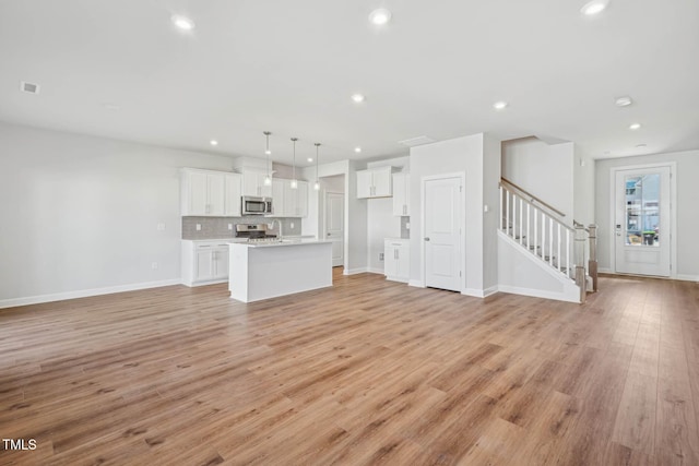 unfurnished living room featuring stairway, light wood-style floors, recessed lighting, and baseboards