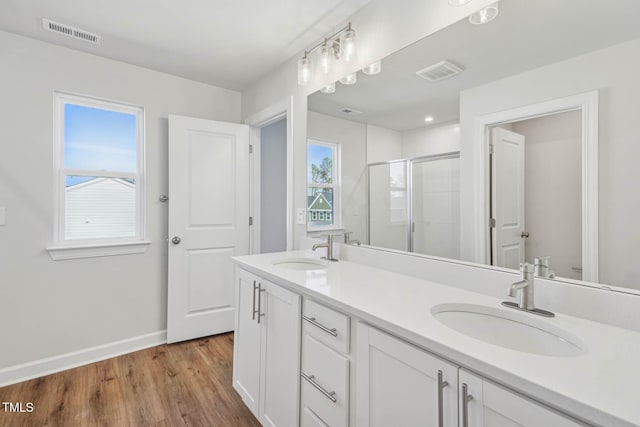 bathroom with a stall shower, baseboards, wood finished floors, double vanity, and toilet